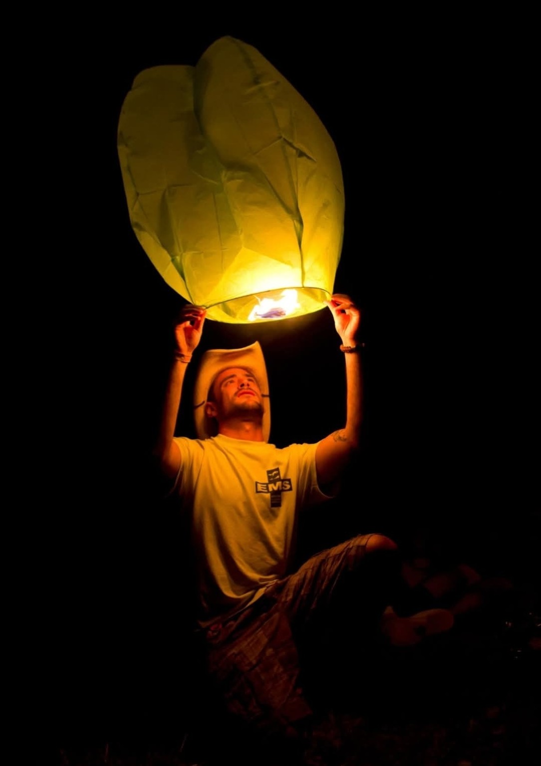 Mark Nicolas wearing an EMS shirt and holding a glowing lantern at a music festival
